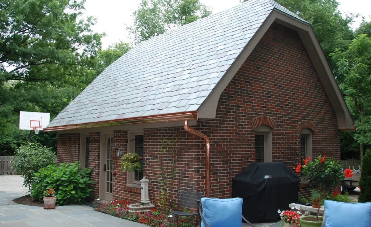 Copper half-round gutters and downspout installed on a brick home exterior